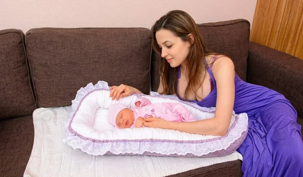 baby on portable newborn bed and mom watching him