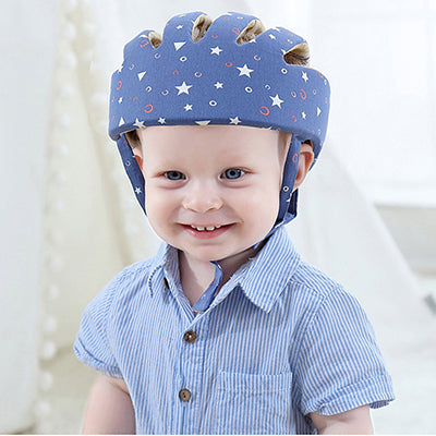 Smiling baby wearing blue star print toddler helmet