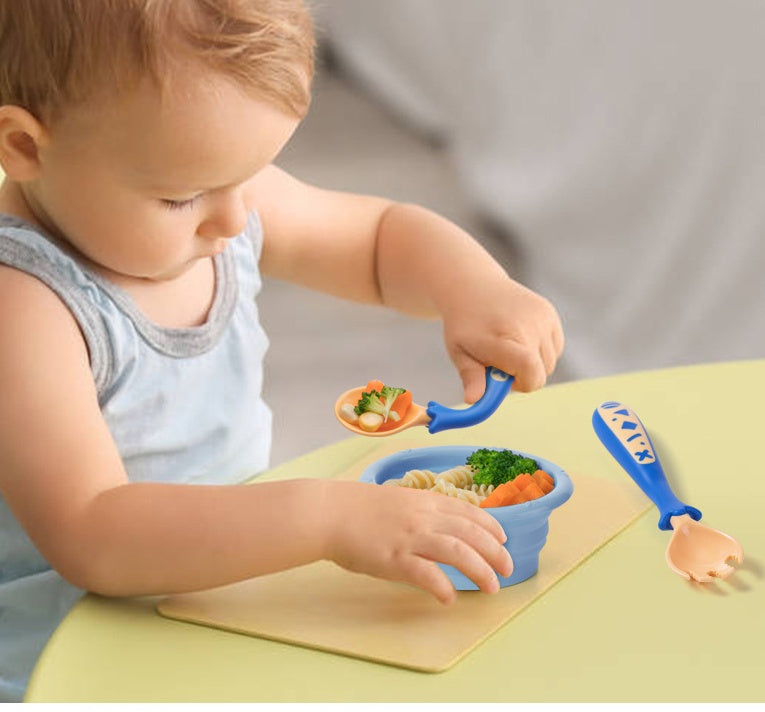 Baby using self feeding spoon set to eat