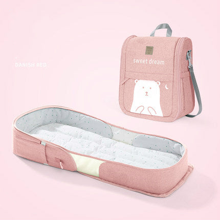 Pink baby crib and carrying case with bear design on a pink background