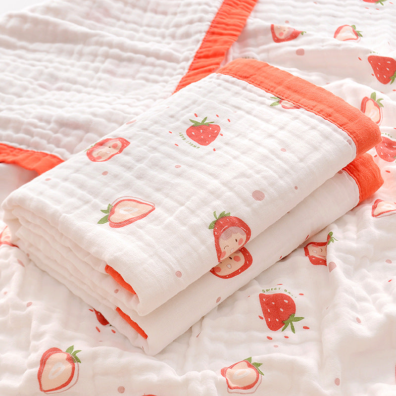  Folded 6-layer muslin cotton swaddle blanket with green trim and dinosaur print, laid on a matching muslin blanket