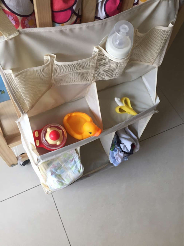 Close-up of hanging crib organizer compartments holding toys, a bottle, and a diaper